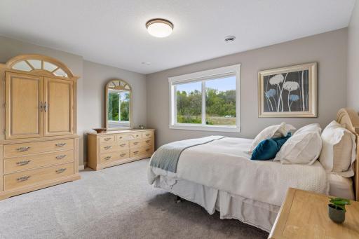 Bright lower-level 2nd bedroom with large window, soft carpeting and spacious layout. Comfortable guest bedroom with peaceful nature views and generous storage space.