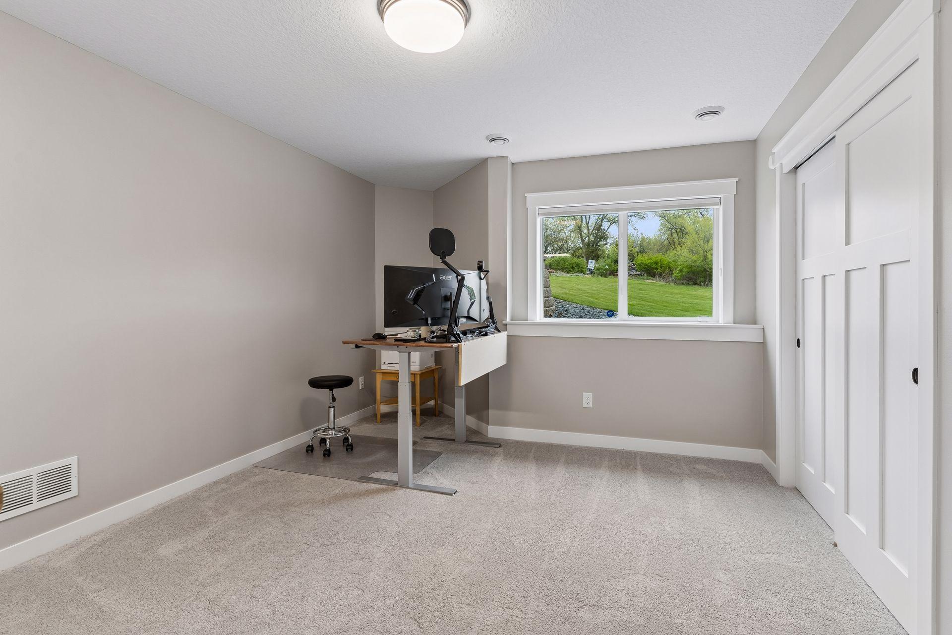 Spacious third lower-level bedroom with large daylight window, plush carpeting, and oversized closet. Comfortable and versatile space for guests, family members or extended stay living.