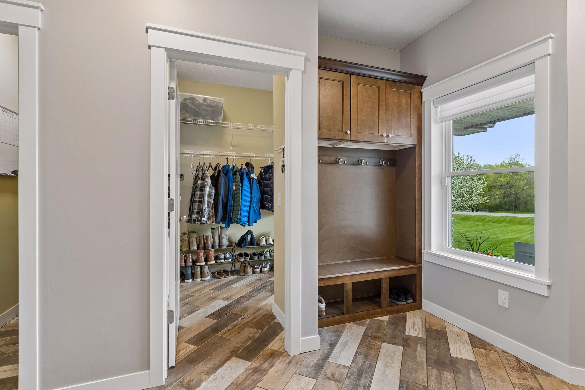 Functional main-level mudroom with custom built-in bench, upper storage cabinets, hooks, and spacious walk-in closet. Convenient garage access and great everyday organization space.