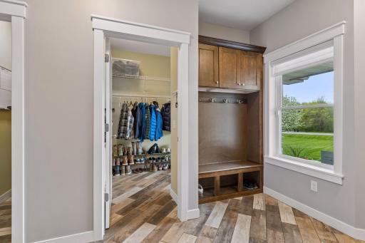 Functional main-level mudroom with custom built-in bench, upper storage cabinets, hooks, and spacious walk-in closet. Convenient garage access and great everyday organization space.