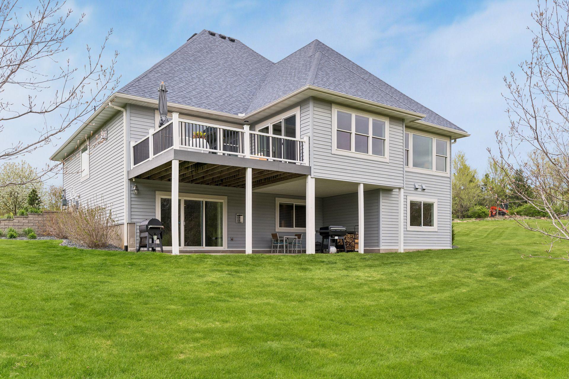 Beautiful rear exterior showcasing the maintenance-free deck, walkout lower level patio, and peaceful private backyard setting with scenic views.