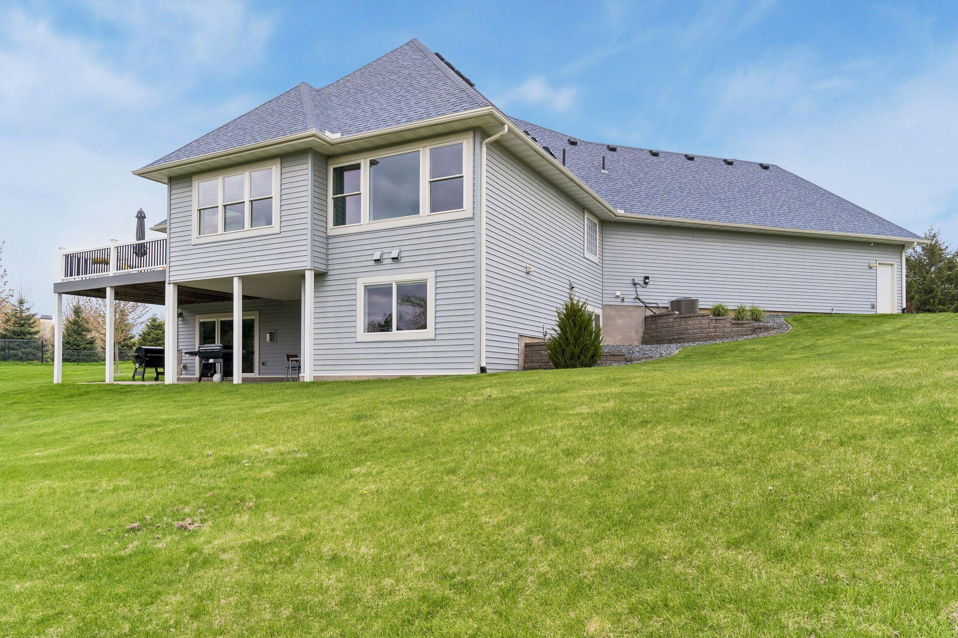 Another rear exterior view highlighting the spacious lot, walkout lower level, and elevated deck overlooking the expansive yard.