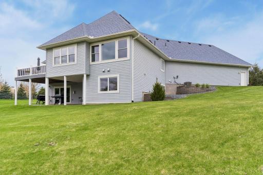 Another rear exterior view highlighting the spacious lot, walkout lower level, and elevated deck overlooking the expansive yard.