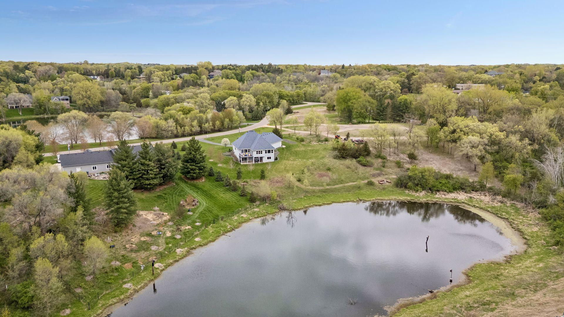 Aerial view showcasing the home's impressive setting surrounded by nature, ponds and upscale neighboring properties.