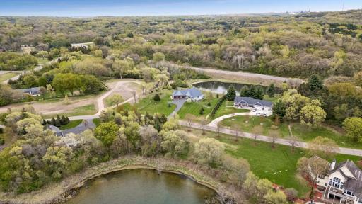 Expansive aerial view showcasing the scenic pond-filled surroundings, mature trees, and spacious private lots in this beautiful upscale neighborhood. Located in the highly desirable 196 School District with nearby parks, walking trails & nature areas