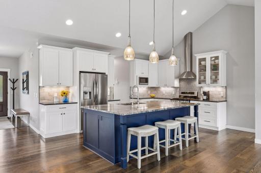 Gourmet kitchen with oversized center island, granite countertops, custom cabinetry, stainless steel appliances, pendant lighting, and abundant prep space. Designed for entertaining and modern luxury living.