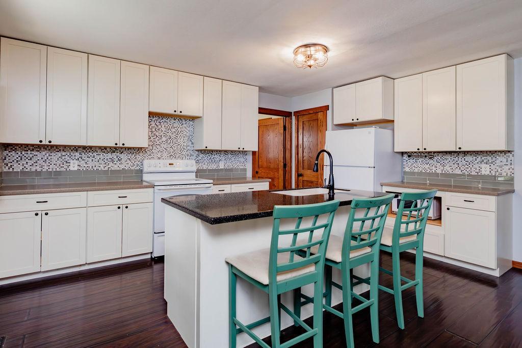 All-white kitchen with center island & seating, tile backsplash,