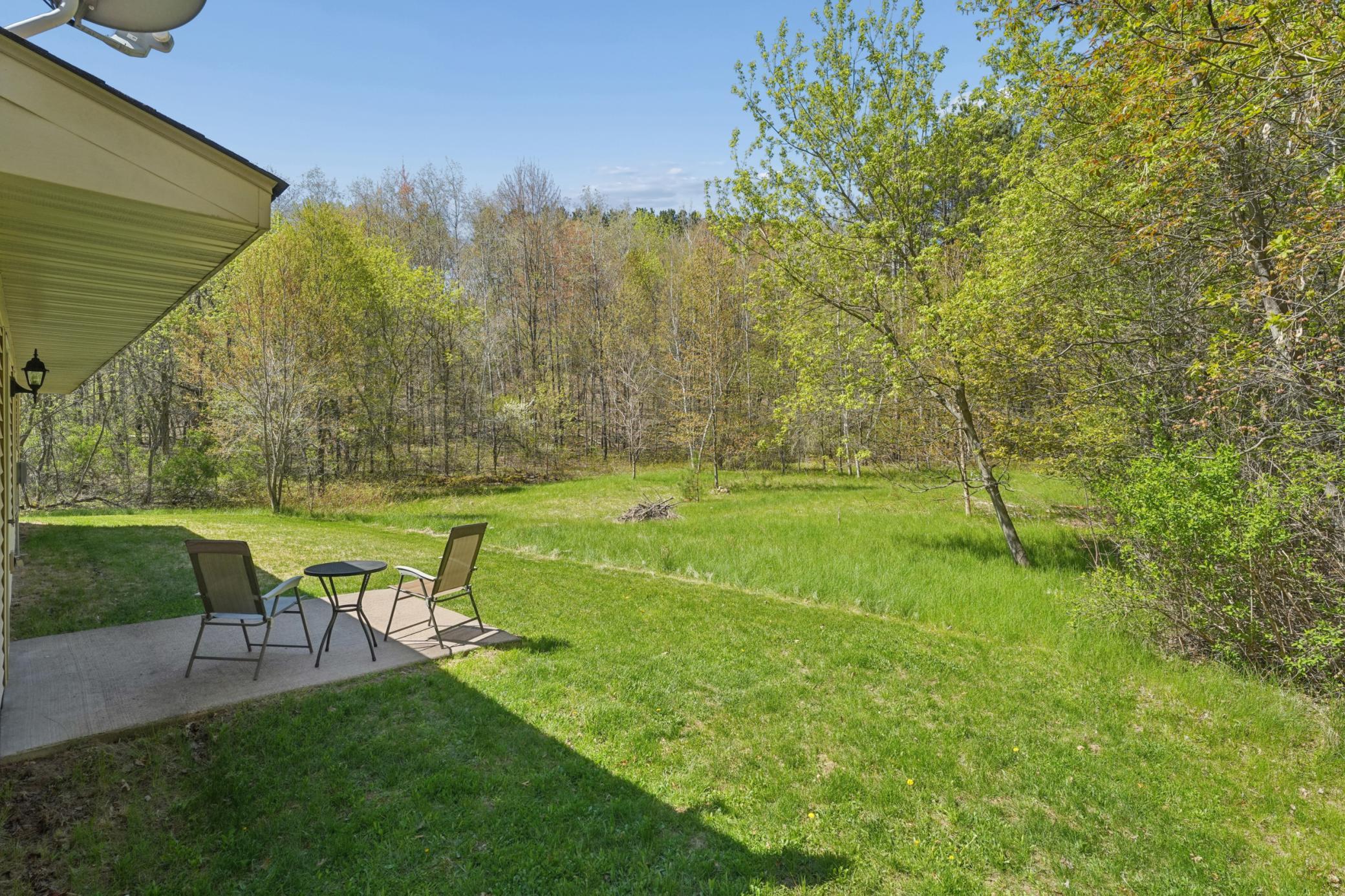 The back service door from the garage has a patio space to sit and enjoy the surrounding nature
