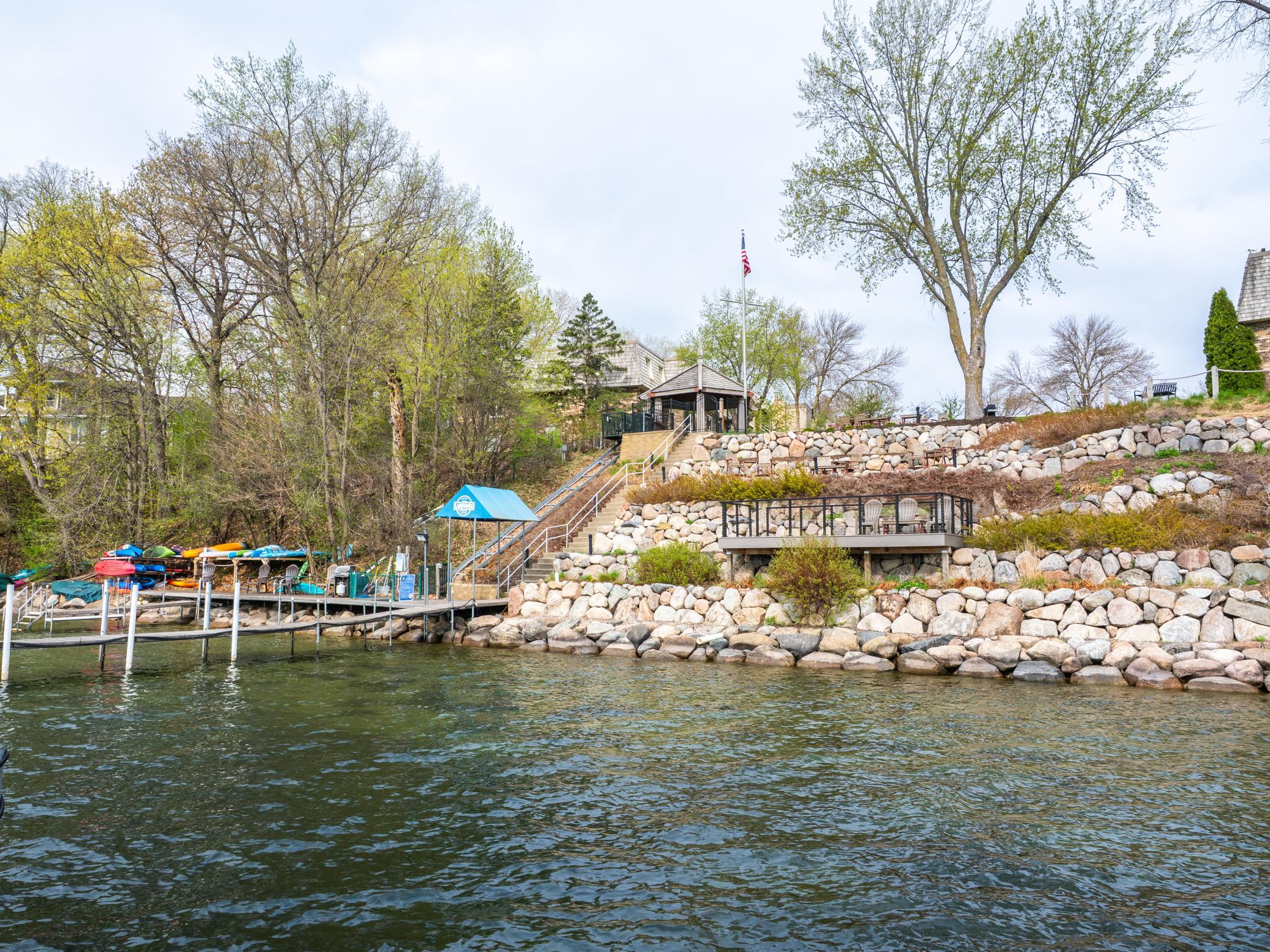 700 ft of shoreline, a sandy swim beach, community dock, lakeside patios with grills and gazebo, a lift for accessibility, kayak storage, and a rooftop Crow’s Nest deck with sweeping panoramic lake views.