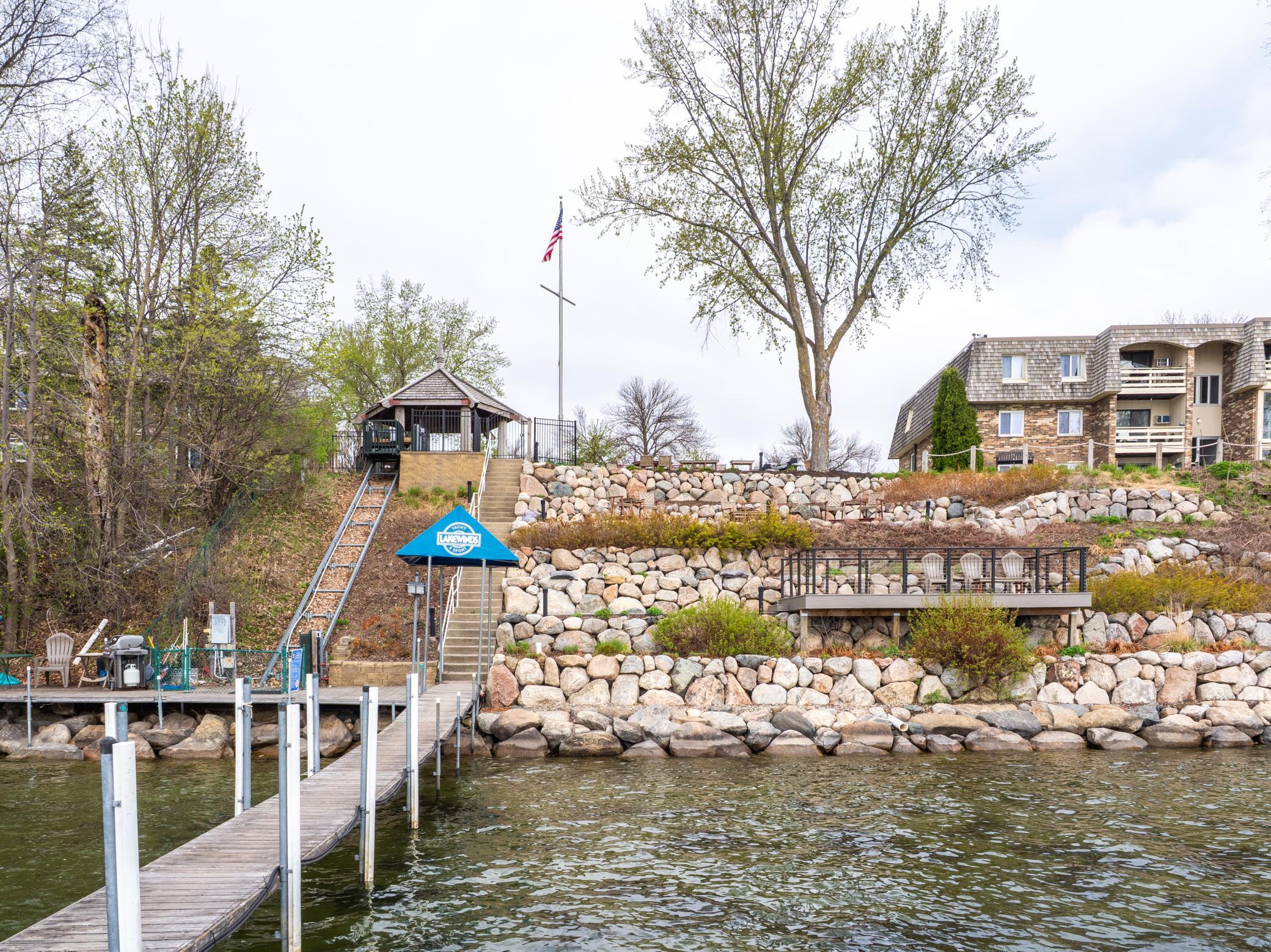 700 ft of shoreline, a sandy swim beach, community dock, lakeside patios with grills and gazebo, a lift for accessibility, kayak storage, and a rooftop Crow’s Nest deck with sweeping panoramic lake views.