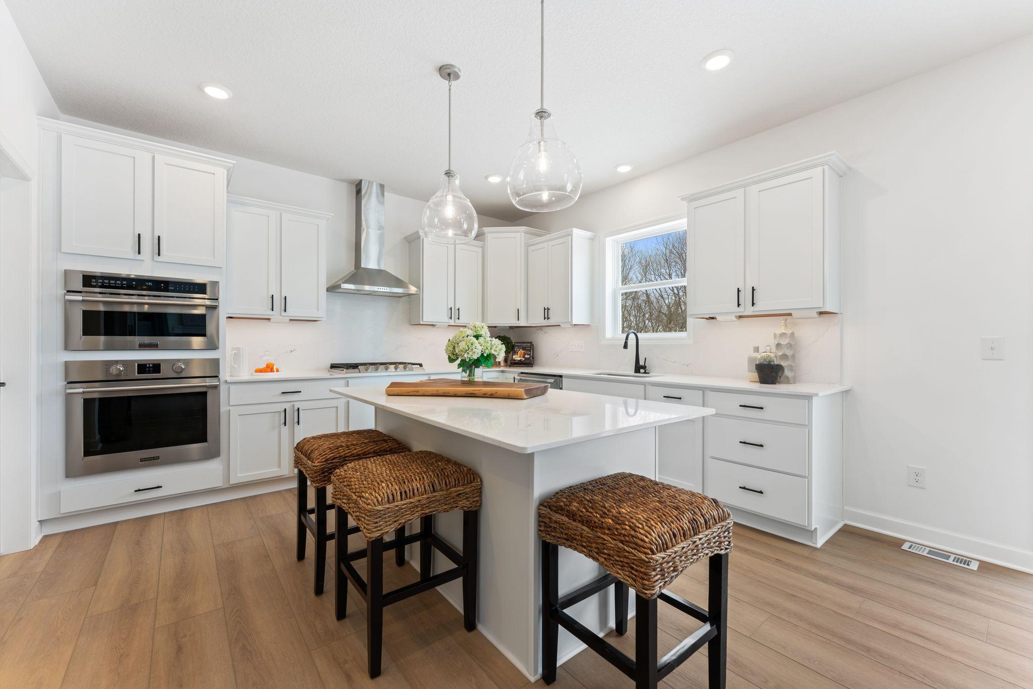 This stylish kitchen showcases a large center island, Shaker-style cabinetry, and brand-new stainless-steel appliances.