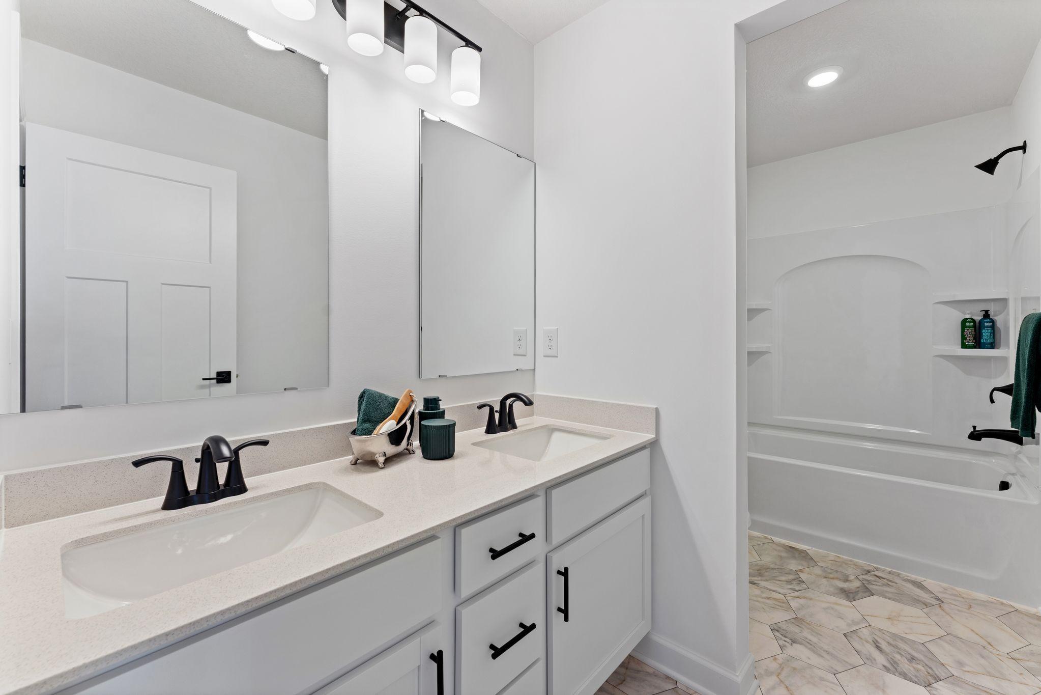 This full bathroom is conveniently located on the second floor and showcases dual sinks and a shower-tub combination.