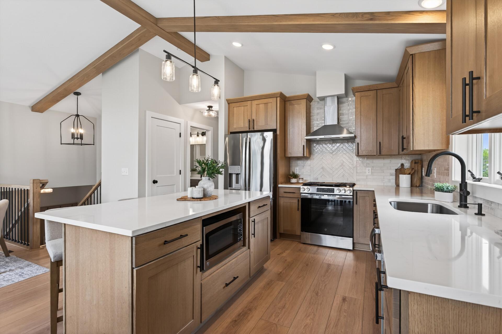 The kitchen is a true showpiece, featuring quartersawn oak cabinetry, quartz countertops, stainless steel appliances, and a large center island with seating and additional storage.