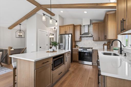 The kitchen is a true showpiece, featuring quartersawn oak cabinetry, quartz countertops, stainless steel appliances, and a large center island with seating and additional storage.