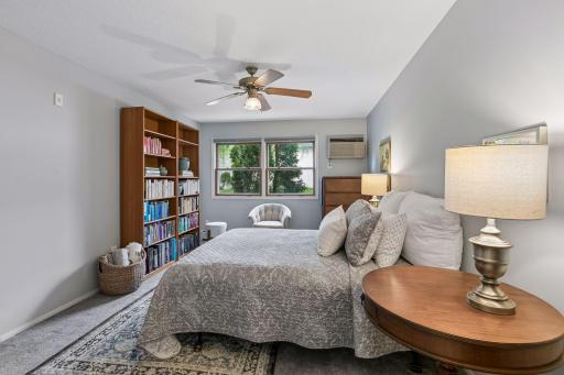 Spacious primary bedroom with windows to green spaces.