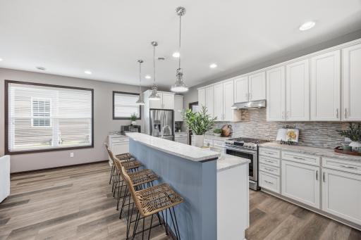 Bright, open kitchen featuring crisp white cabinetry, stainless steel appliances, and a spacious center island with seating.