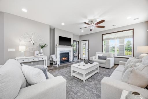 View of cozy gas fireplace with mounted TV and large, bright windows and access to porch and backyard and primary bedroom. All windows have Hunter Douglas window treatments.