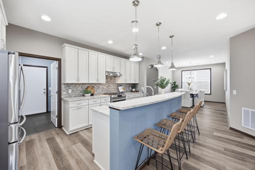 Spacious kitchen with oversized island, pendant lighting, and seamless flow to the large formal dining area.