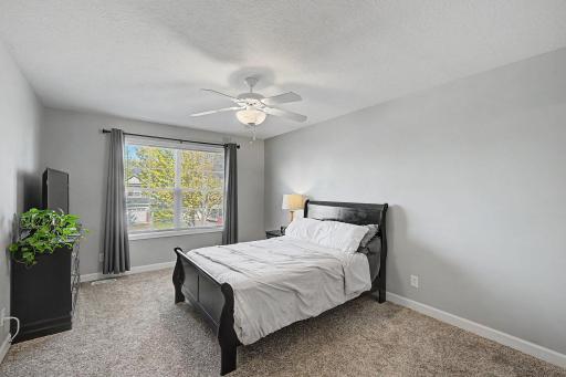 Spacious primary suite with large window and ceiling fan.