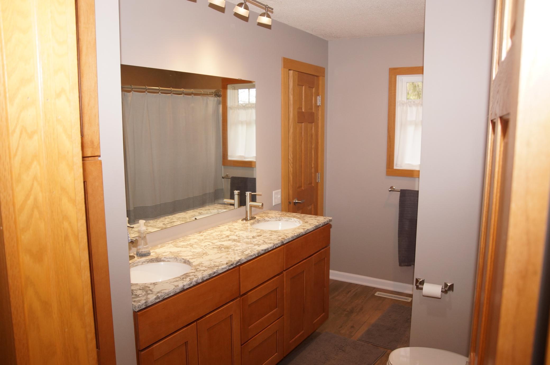 Main Bathroom walks through from 1st Bedroom and Features Quartz Counters with Double Sinks, Upgraded Fixtures and Full Tub Surround!