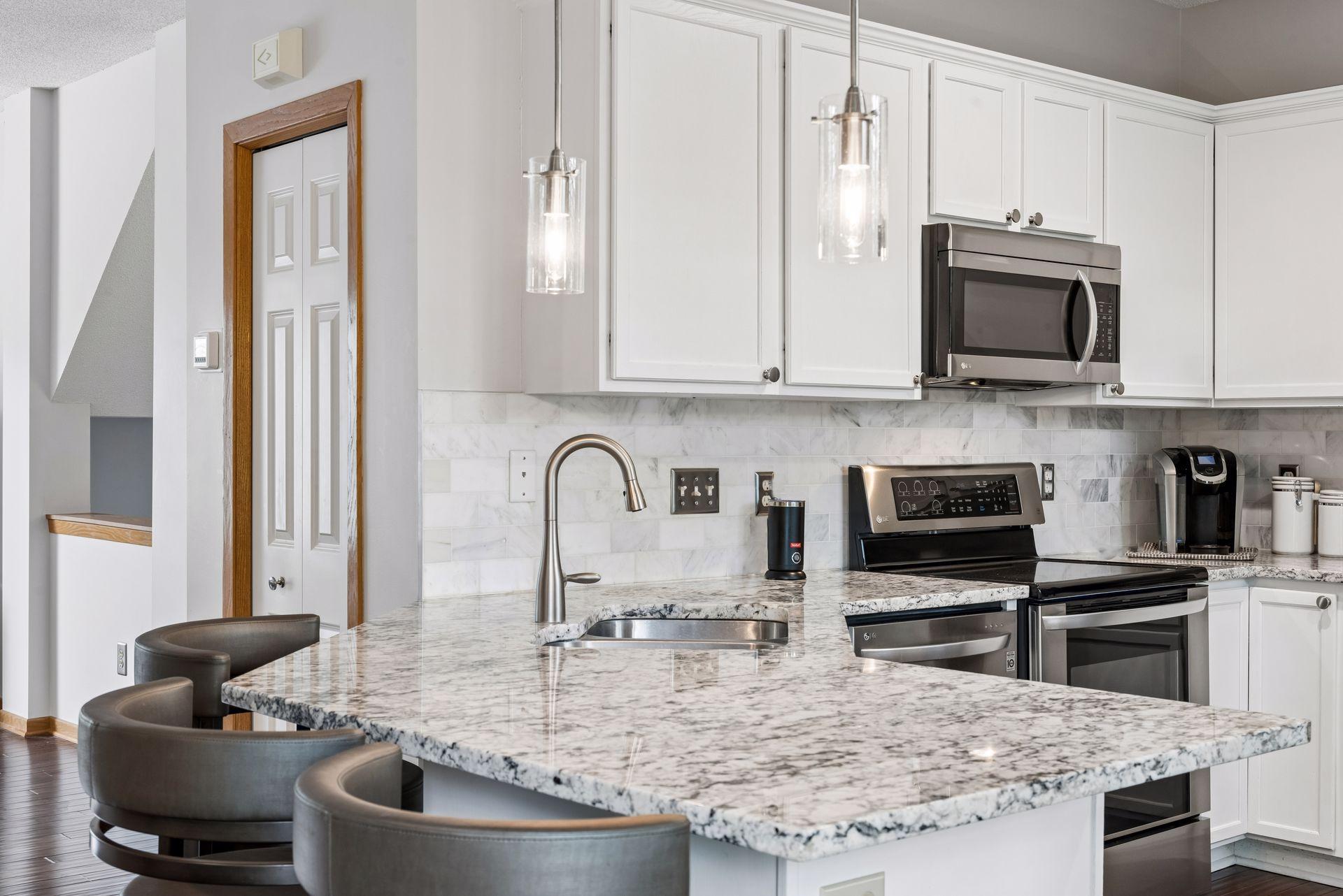 The kitchen has been redone and features granite countertops, an extended breakfast bar, tile backsplash, tasteful white cabinets, and stainless appliances.