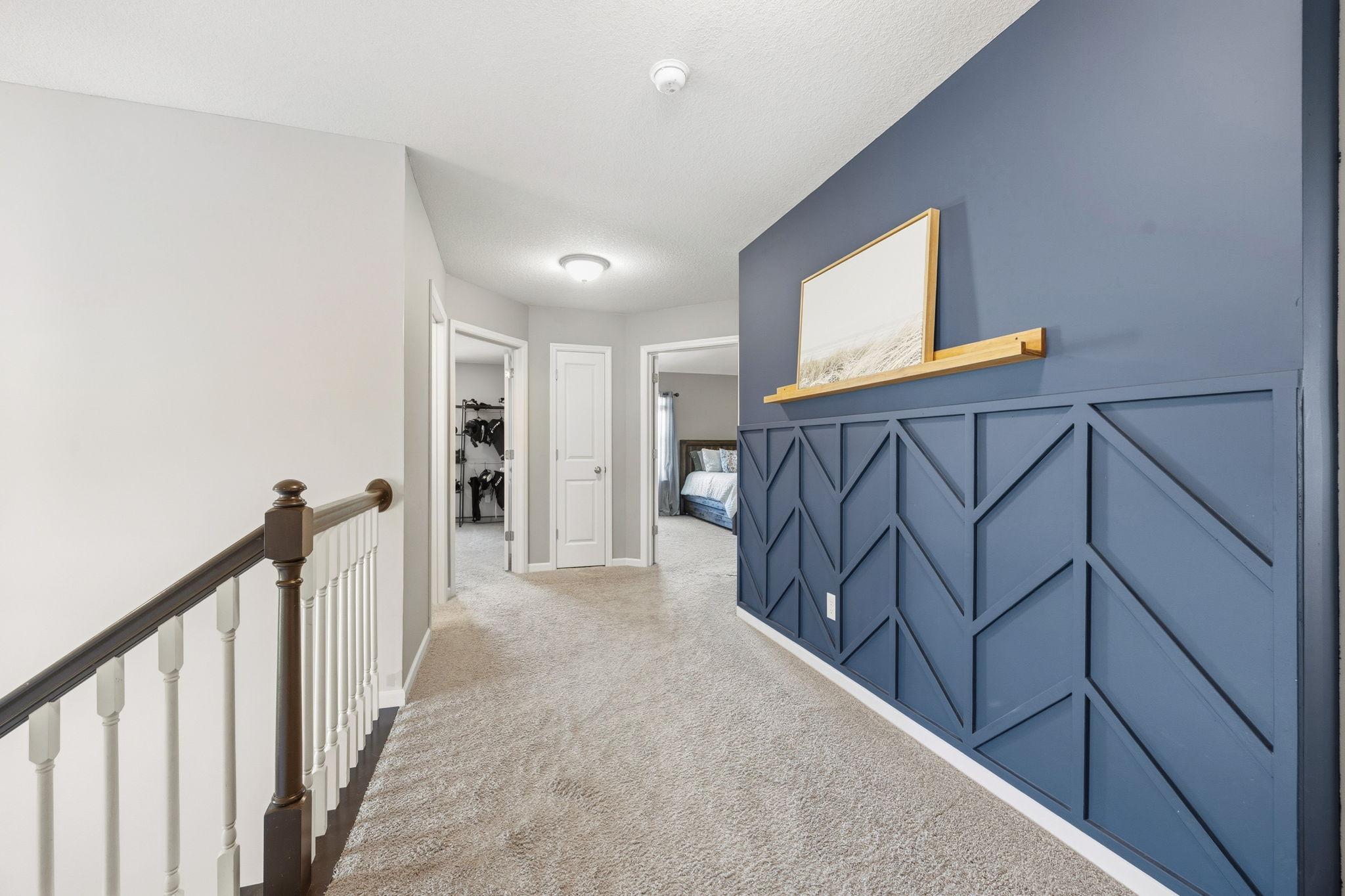 Spacious upper-level hallway with custom accent wall detailing.