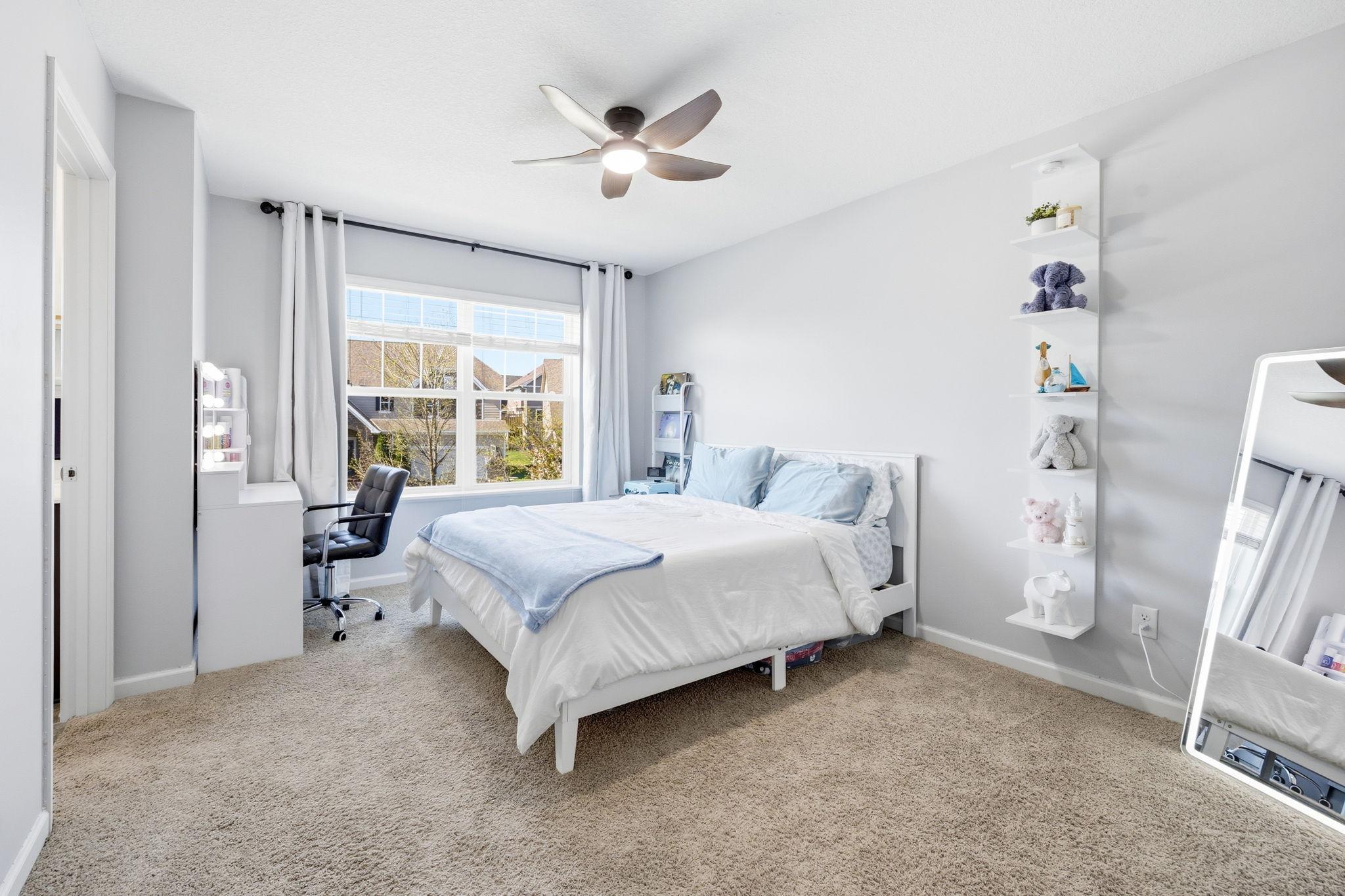 Bright upper-level bedroom featuring oversized window, plush carpeting, and generous space for a bed, desk, or cozy reading nook.