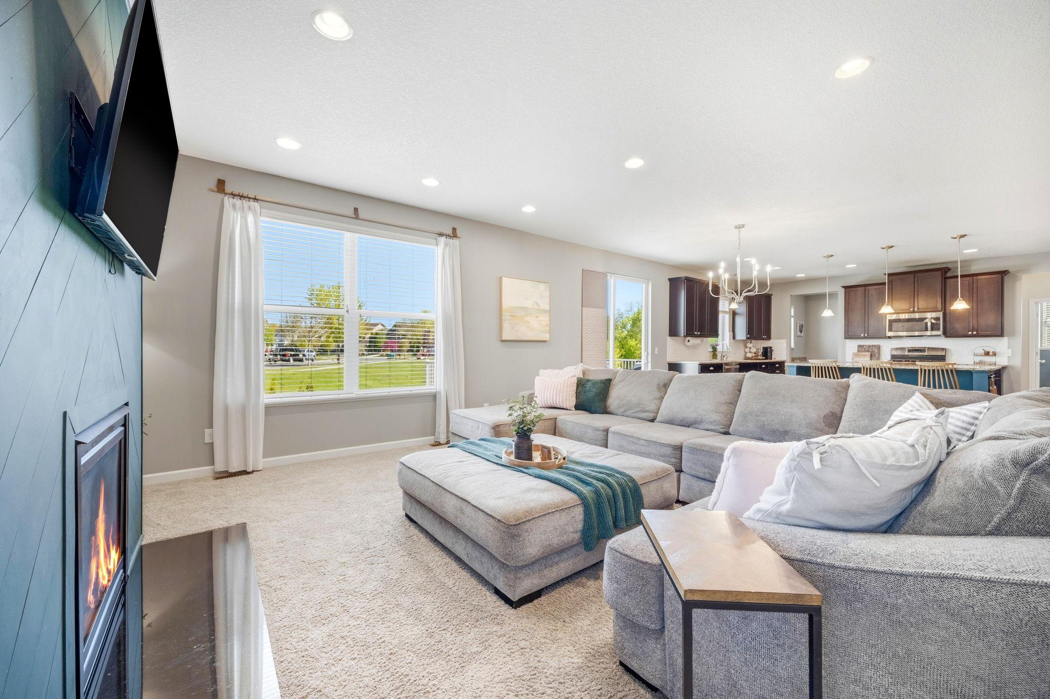 Comfortable and inviting open-concept living space featuring a cozy gas fireplace, expansive windows with natural light, and seamless flow into the kitchen and dining areas.