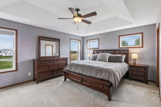 The primary bedroom has a vaulted tray ceiling w/ a ceiling fan and with clerestory windows to maximize the natural light in the room.