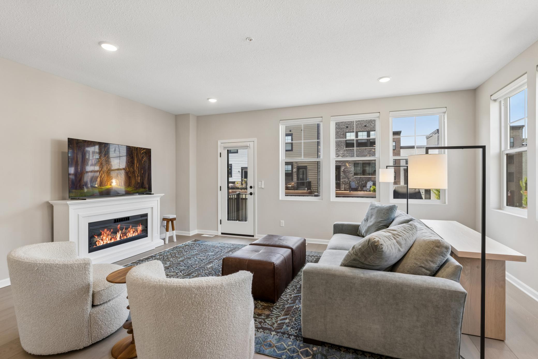 Spacious living room with deck access for grilling, custom window treatments with remote shades in the living areas and an electric fireplace.