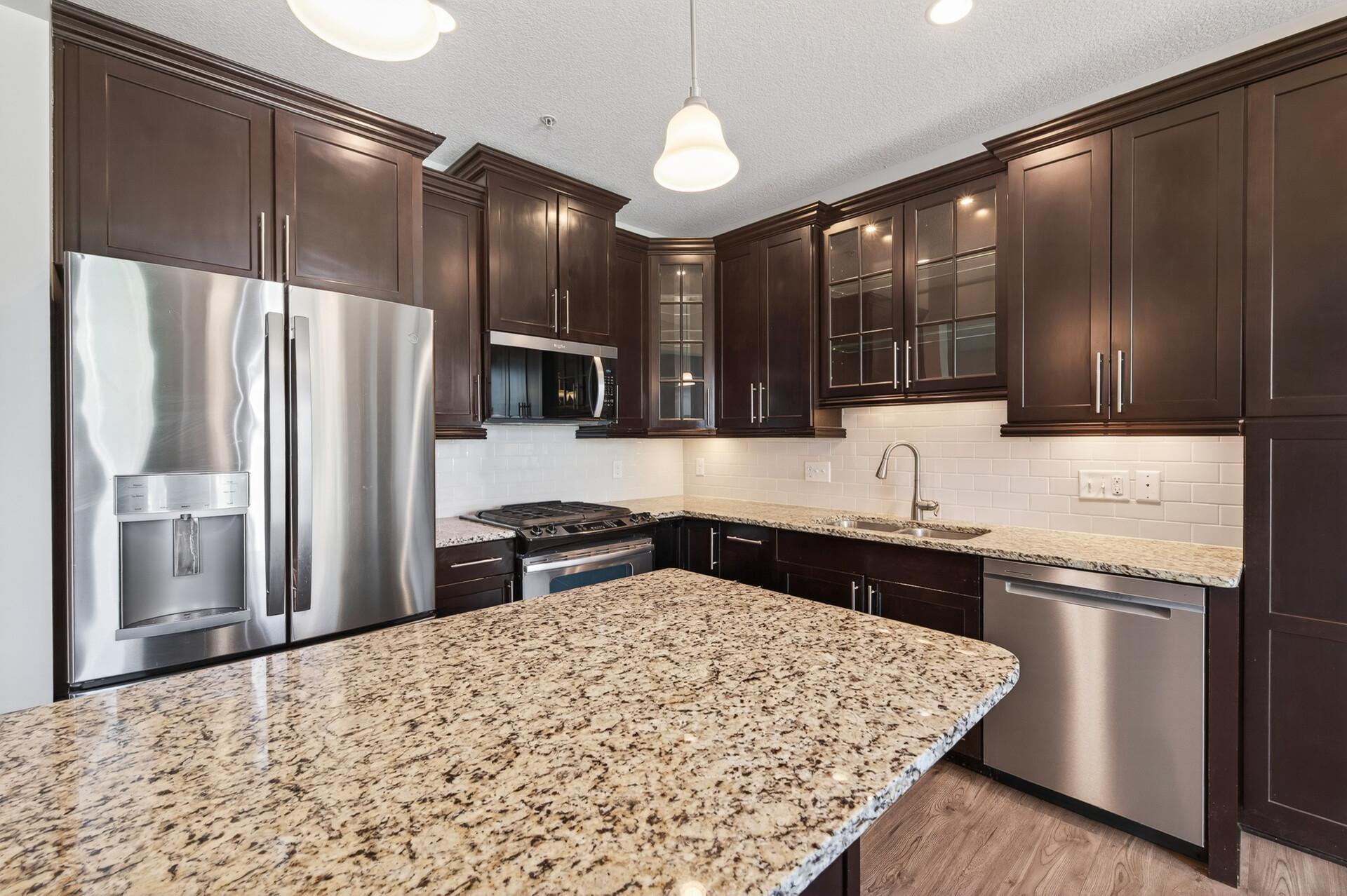 Beautiful kitchen with center island, stainless appliances, cabinets with glass doors.
