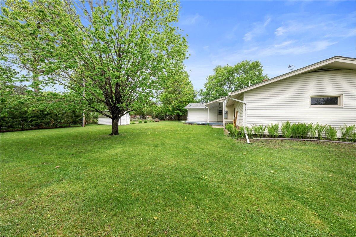Expansive backyard surrounded by mature trees offers beauty, shade, and privacy year-round.