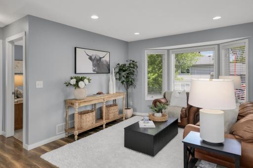The living room is anchored by large windows that flood the space with natural light and provide views of the backyard, while the cozy seating arrangement adds a comfortable, welcoming feel.