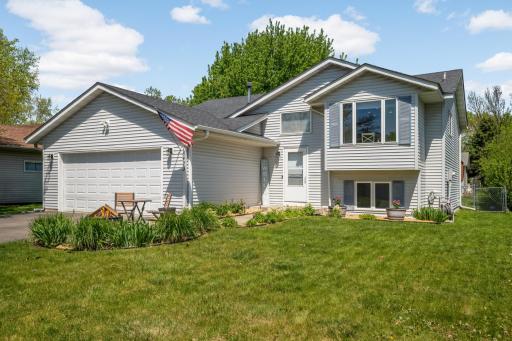 WELCOME HOME to this well-maintained split-level home with light gray maint free siding with white trim, and a dark charcoal roof that sits on a beautifully landscaped lot under a bright blue sky.