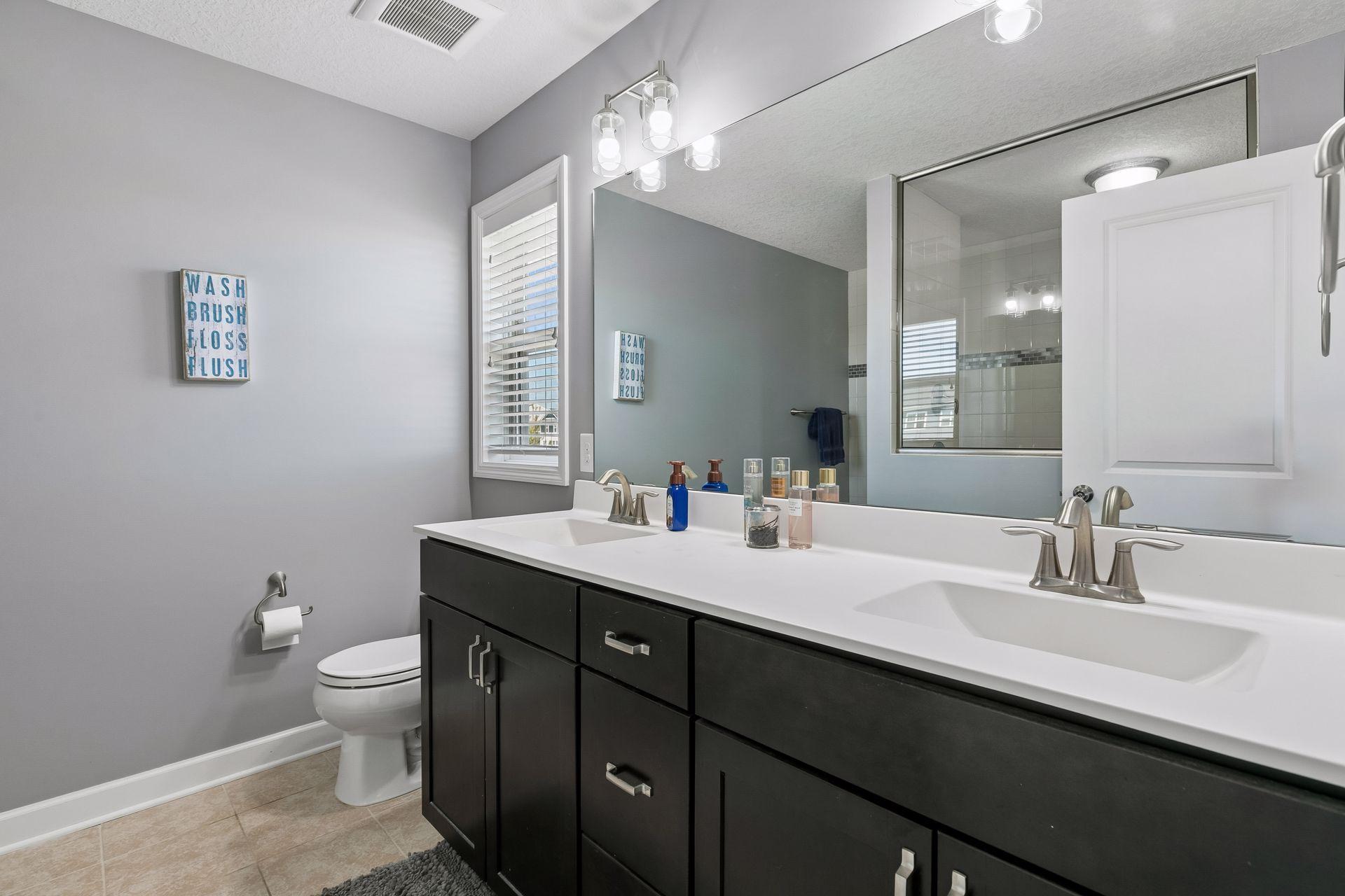 Primary bathroom featuring dual vanities and a large tiled shower.