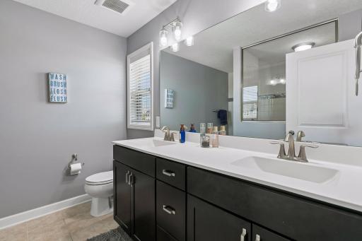 Primary bathroom featuring dual vanities and a large tiled shower.