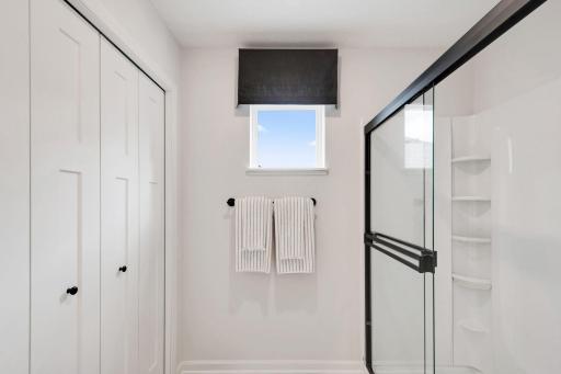 Owner's bath features a shower and large linen closet, plus a window placed higher on the wall for natural light.