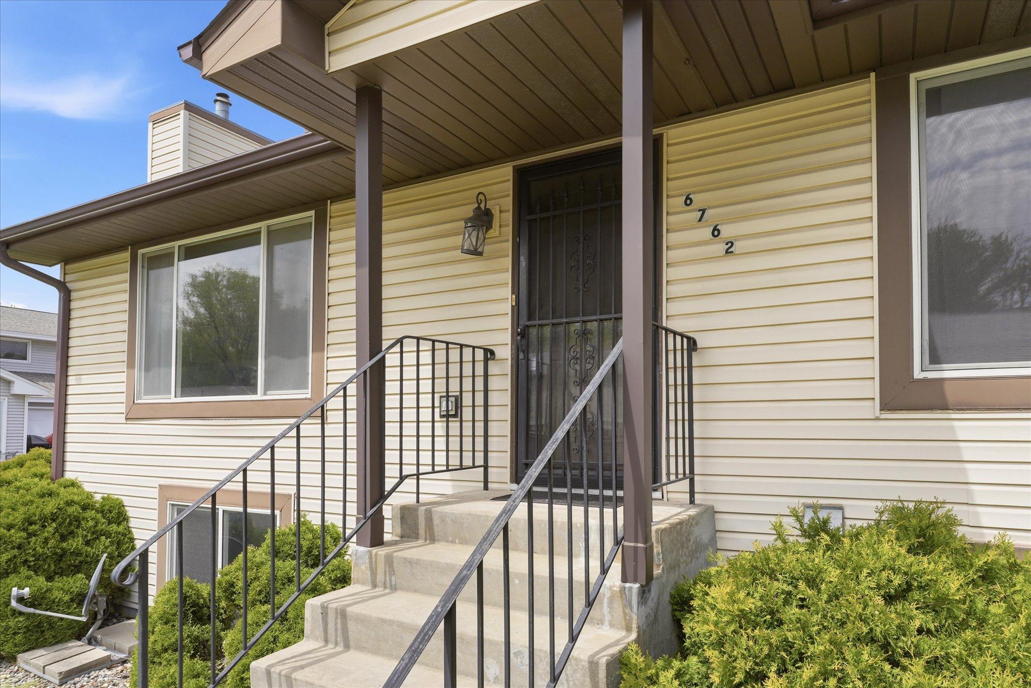 Covered front entry with updated lighting and inviting staircase creates a warm welcome for guests and visitors.