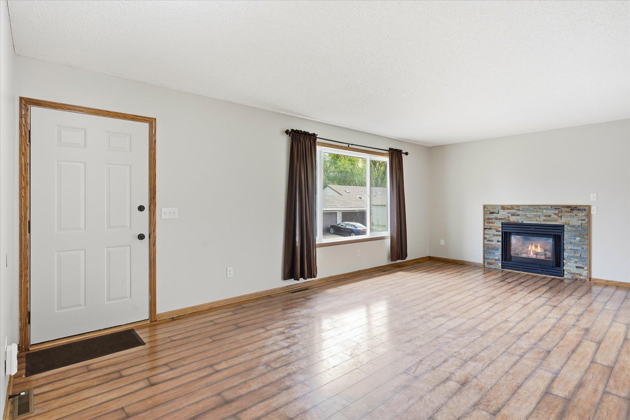 Large picture window fills the living room with natural light while the cozy gas fireplace creates a warm and inviting focal point.