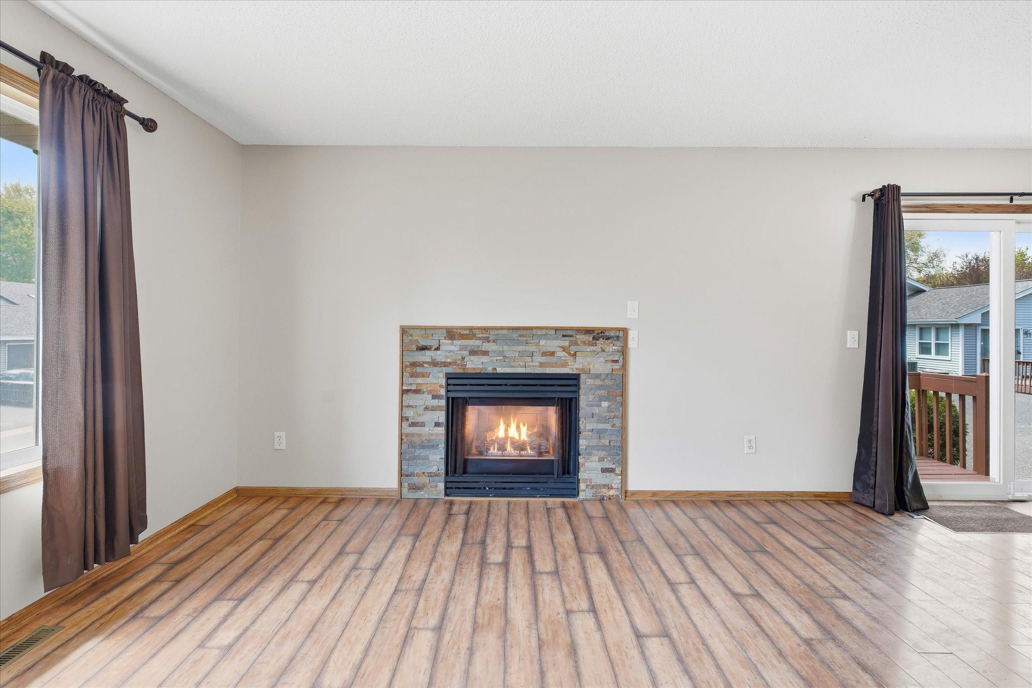 Bright and open main living space featuring updated flooring and beautiful stone-surround gas fireplace.