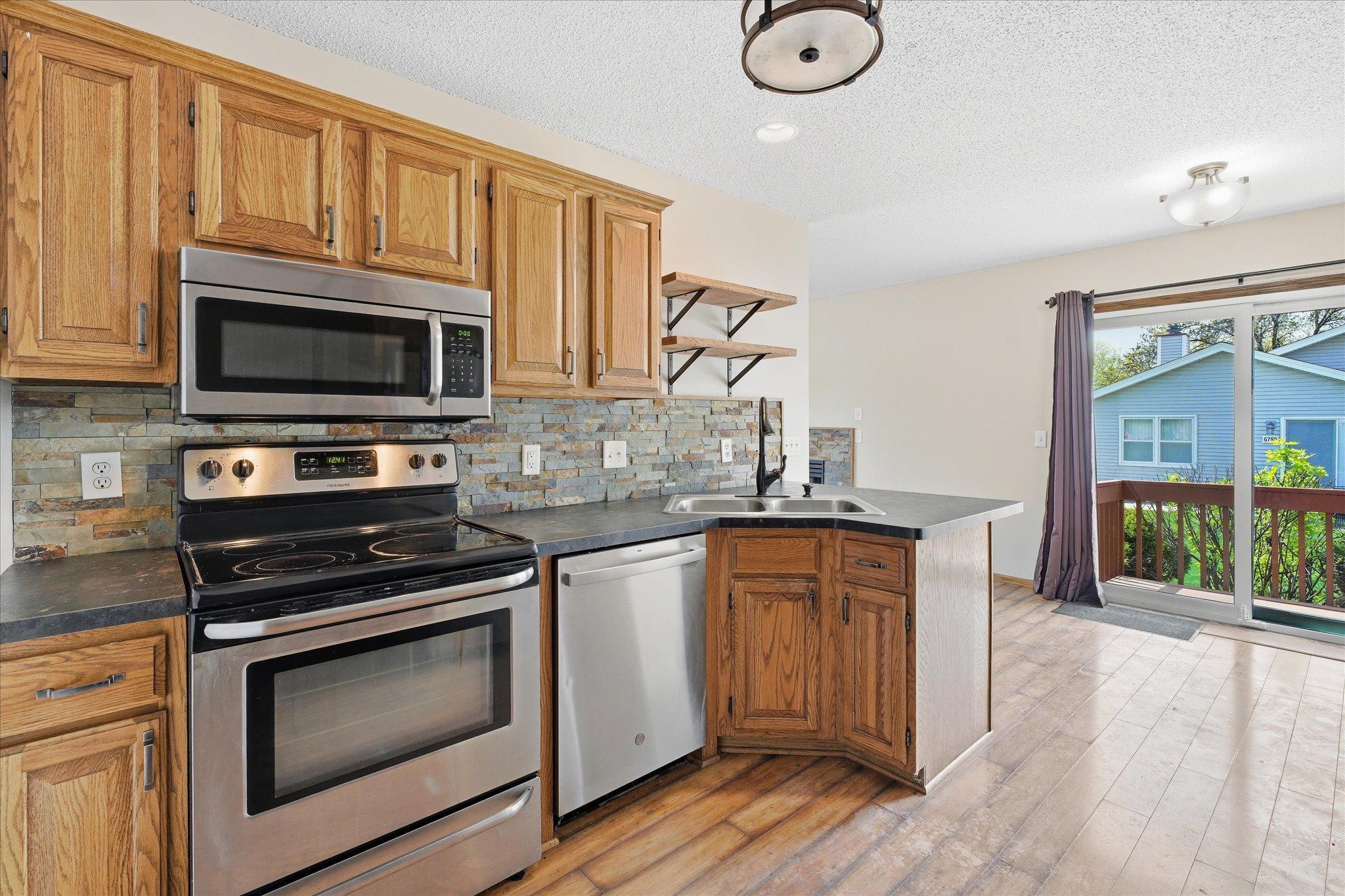 Functional kitchen with stainless steel appliances, abundant cabinetry, and stylish tile backsplash.