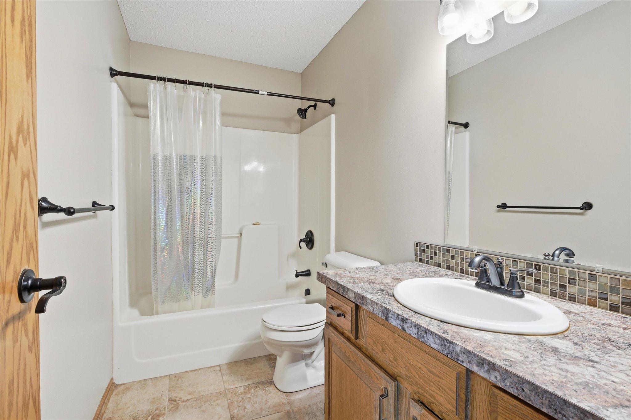 Updated full bathroom with modern fixtures, attractive vanity, and easy-maintenance tub/shower surround.