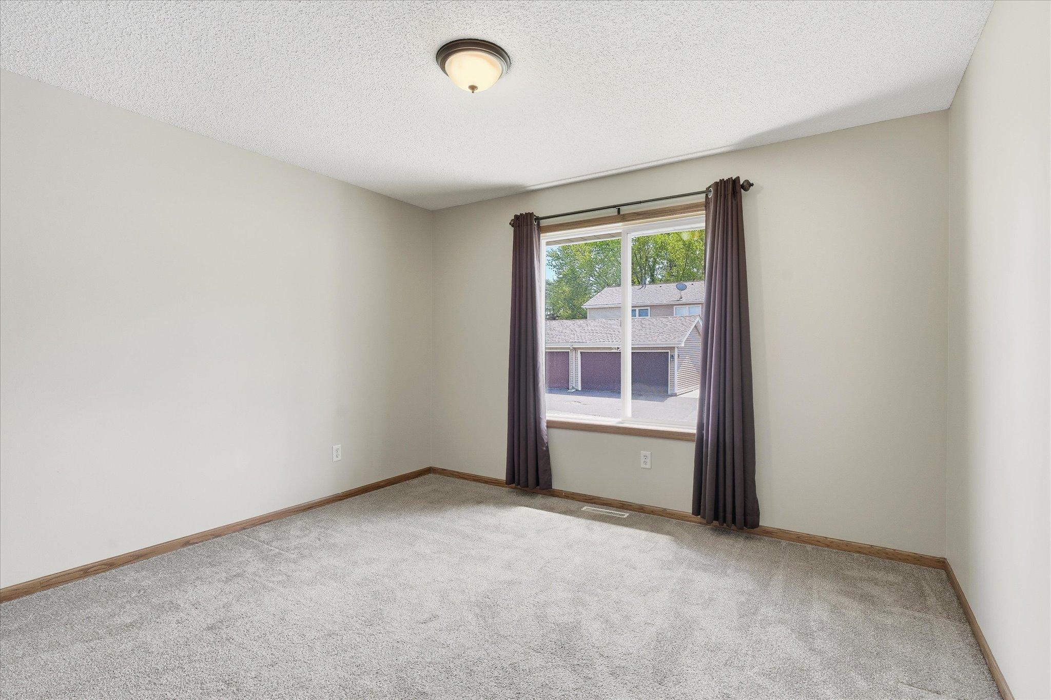 Spacious primary bedroom on the main level with plush newer carpet, neutral paint tones, and plenty of room for larger furniture arrangements.