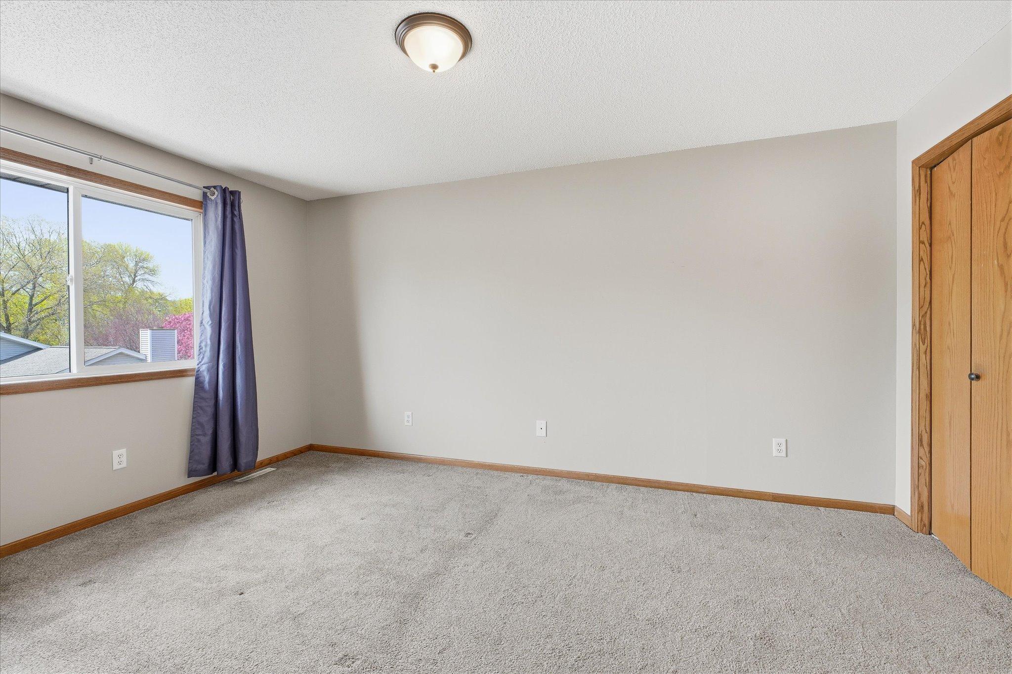 Spacious upper level primary bedroom with neutral décor, plush carpet, generous closet space and a private full bath.