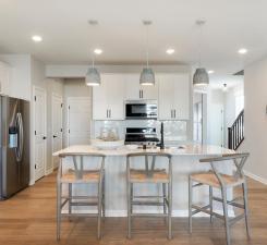 The Ashton's kitchen features a huge island surrounded by even more quartz counters. Durable and beautiful is a great combo! Photo of model home.