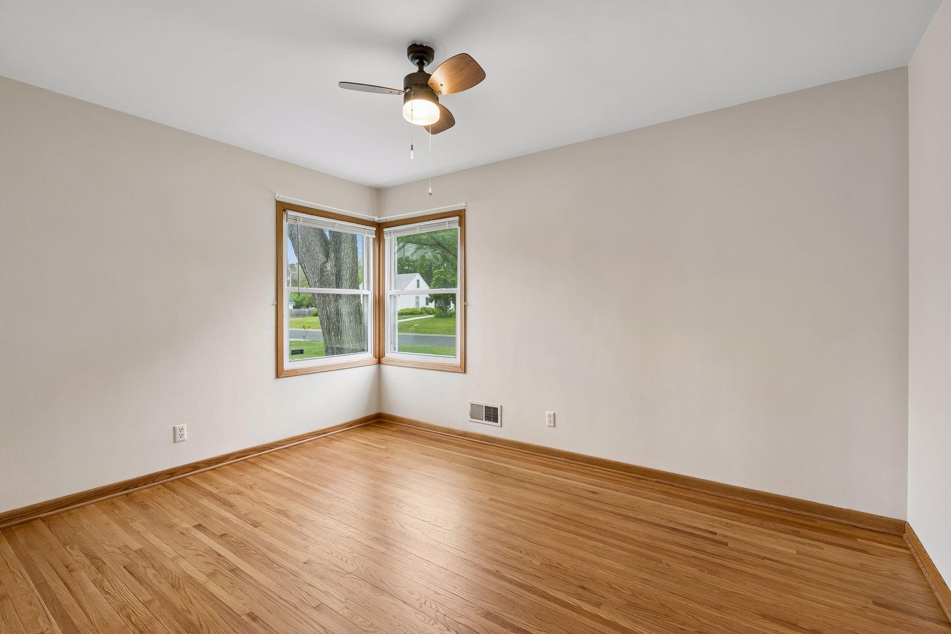 Primary bedroom with wood floors and corner windows