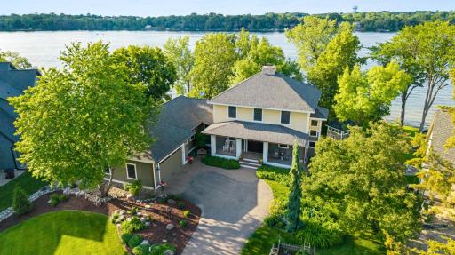 Set on .56 acres along Lower Prior Lake, the home is surrounded by mature trees, established gardens, stone paths, covered porches, and outdoor spaces that lead naturally toward the shoreline.