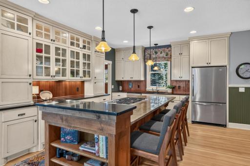 Kitchen features custom enameled cabinetry that offers full overlay flat paneled doors, glass doors with interior accent lighting, full height uppers, roll-out storage and under cabinet accent lighting