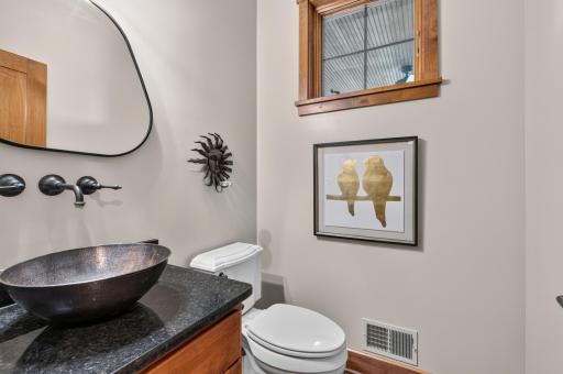 Main Level 1/2 bathroom features alder vanity cabinet with granite top and copper vessel sink. Mosaic tile flooring