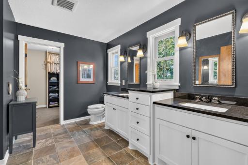 Master Bathroom features pair of enameled cabinets with linen tower, topped with granite countertops. Natural slate tile flooring